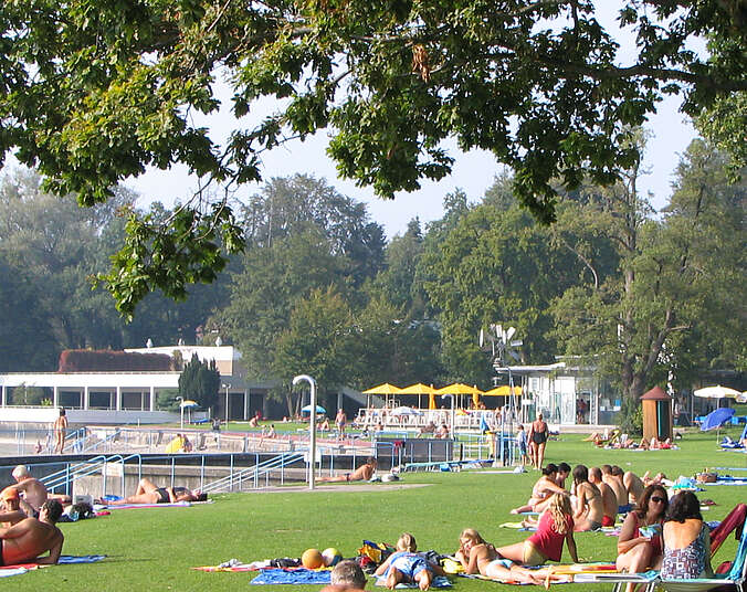 Menschen liegen auf der grünen Wiese im Strandbad am See
